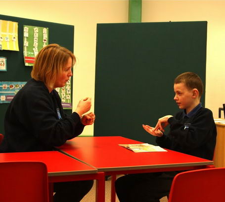 A boy and his teacher use British Sign
                  Language