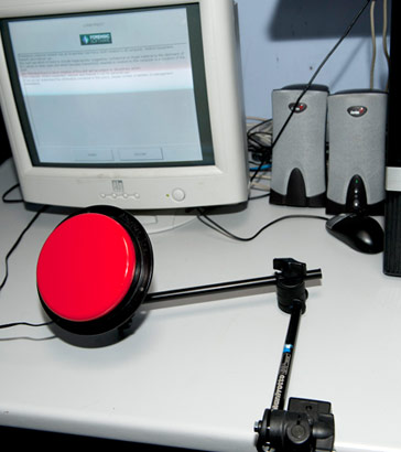 Articulated clamp holding large
                  red button in front of computer monitor