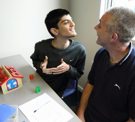 Boy in grey Nike top smiles at the teacher
                  that he is sitting next to