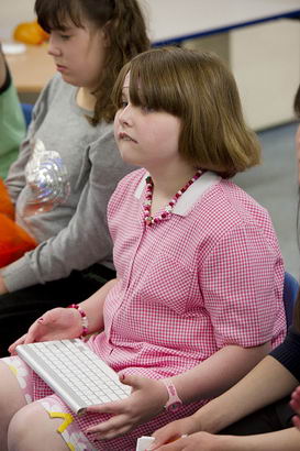 A young girl seated using a keyboard