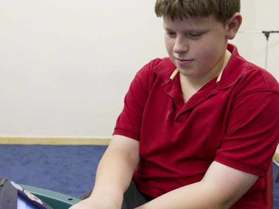 teenage boy speaks using aid