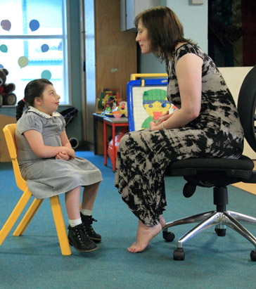 barefoot teacher with girl on chair