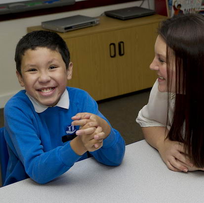 Young boy and female teacher at
                  school desk