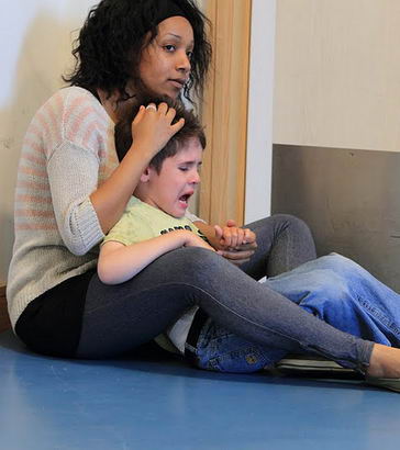 A carer holds a distressed boy