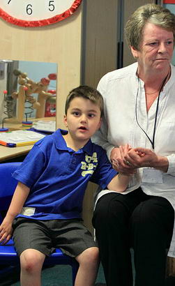 A carer holds a boy's hand