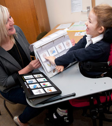 Girl and teacher using a communication
                  device and cards