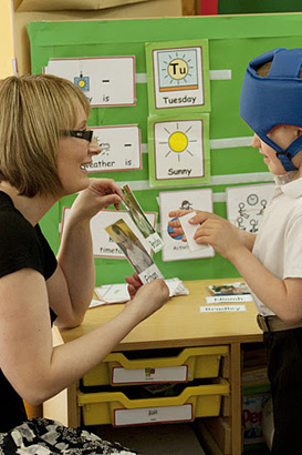 A young boy and his teacher interact
                  using a garden gnome picture