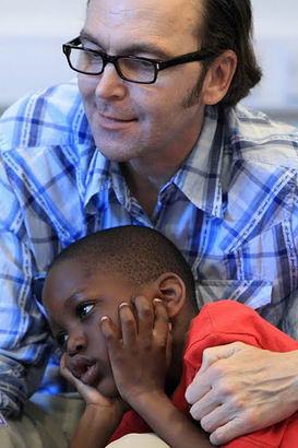 A young boy and his teacher interact using a garden gnome picture