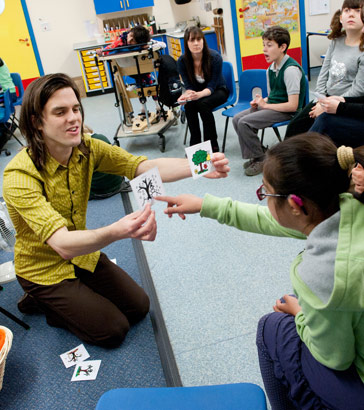 A girl points to a card held by
                  a teacher