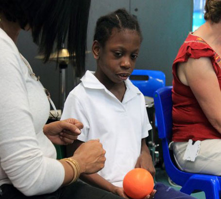 A male teacher smiles with one boy whilst
                  another boy lies on his lap