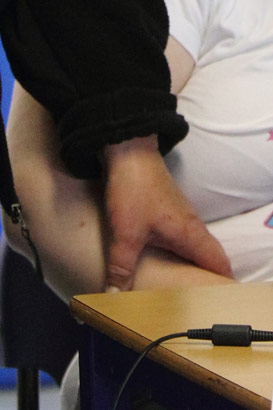 A carer holds a young girl's hand to calm
                  her