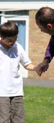 A boy holding his carer's hand