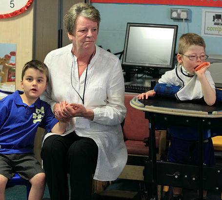 A carer holds a boy's hand