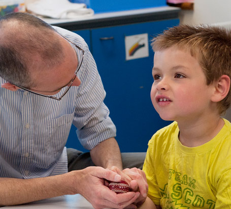 A distressed boy being held and
                  calmed by his carer