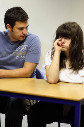 A girl and adult sit next to each other
                  at a table