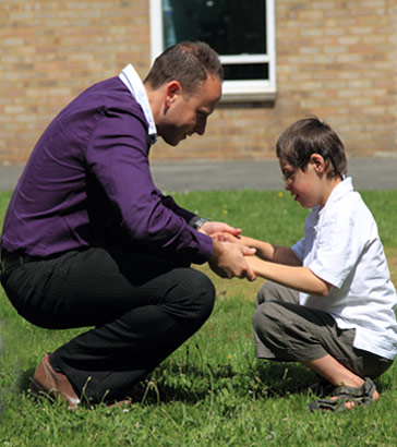 A young boy and his teacher interact using
                  a garden gnome picture