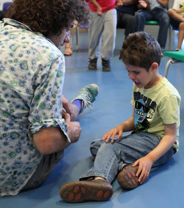 An upset boy and his carer sit on the floor