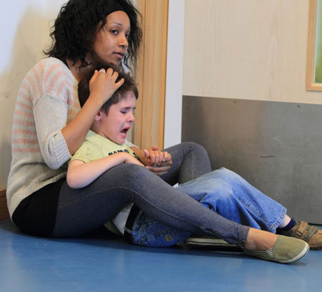 A distressed boy being held and calmed by his carer