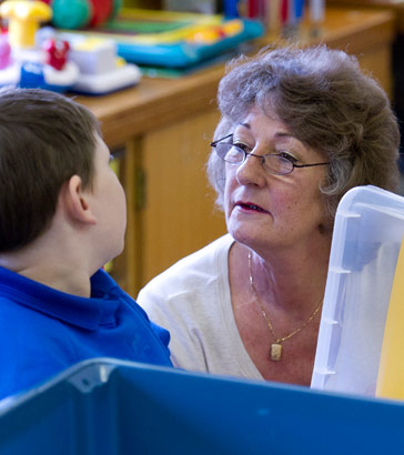 A teacher talking to a boy sitting
                  at a table