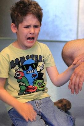 A carer holds an upset boy's hand