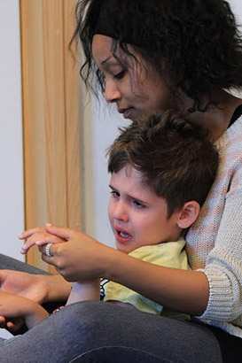 A teacher comforts a young boy who is distressed