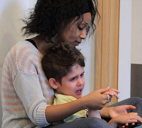 A teacher comforts a young boy who is distressed