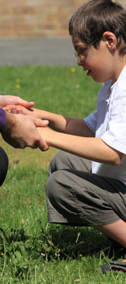A boy holding his carer's hand