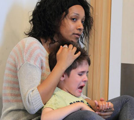 A young female teacher comforts an anxious young boy