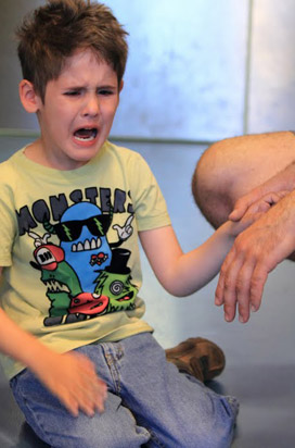 The same young boy is reassured by his teacher