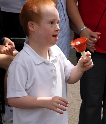 Contented young boy ring hand bell in
                  crowd