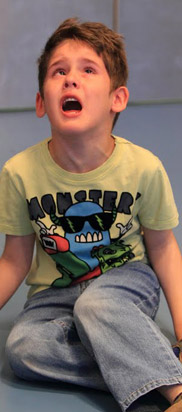 A young boy sits on the floor in a distressed state