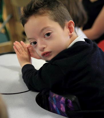 A boy in a standing support turns to the
                  camera