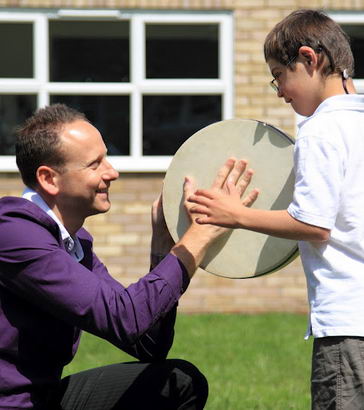 A boy and his teacher play a drum