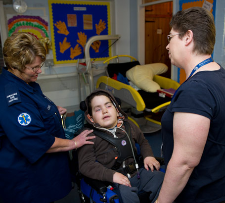 A care-assistant and a teacher assist
                  a boy in a wheelchair