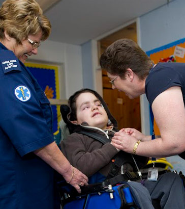 A boy in a wheelchair with two carers