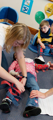Two carers help with a child's leg
                  splints