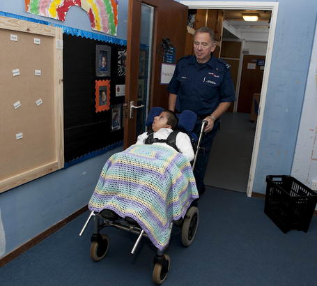 A boy covered in a blanket is
                  wheeled along a corridor
