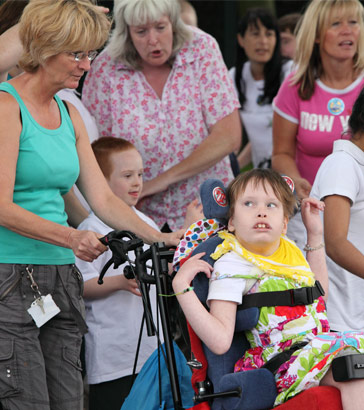 A girl in a wheelchair amongst a group of
                  children and adults
