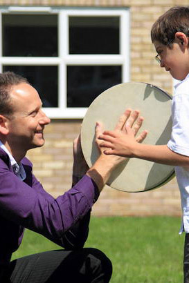 Teacher showing a boy how to play
                  the drum