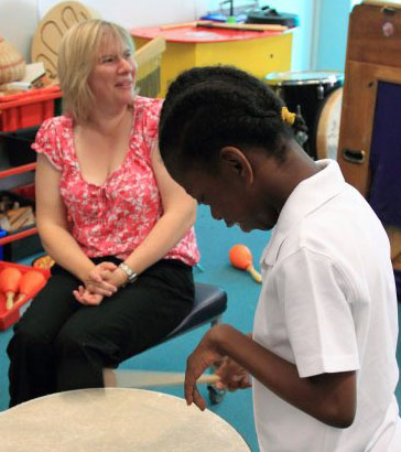 Teacher helping a boy understand an activity
                  card