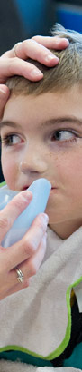 A carer helps a boy to drink from
                  a cup