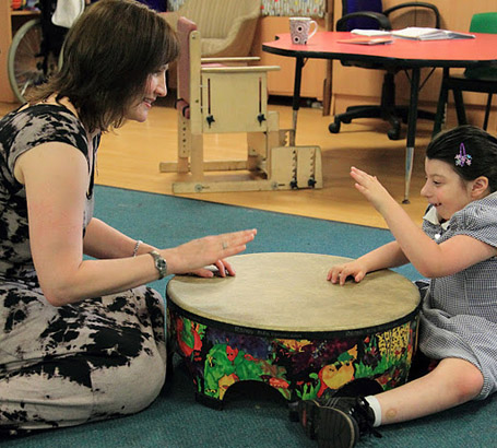 A girl and her teacher play a large drum