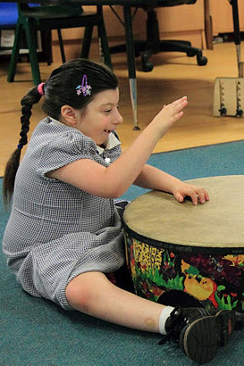 A girl and her teacher play a large drum