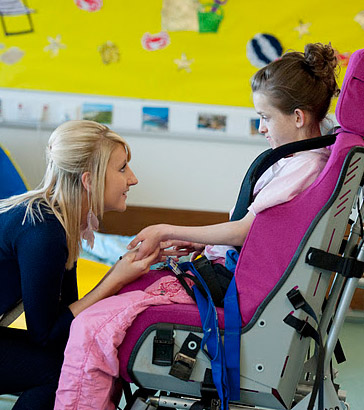 A teacher holds the hands of a
                  girl in a wheelchair