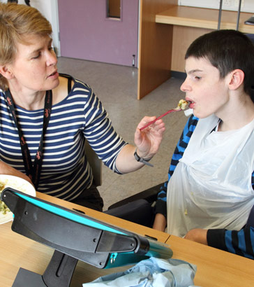 A boy being fed by his carer