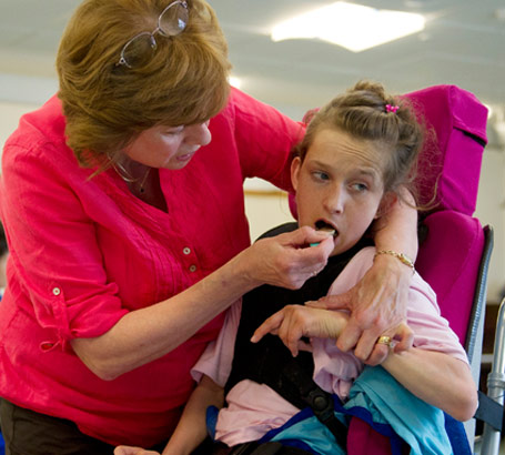 A carer helps to feed a girl