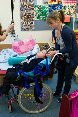Two carers ensure that a child is
                  comfortable in a wheelchair