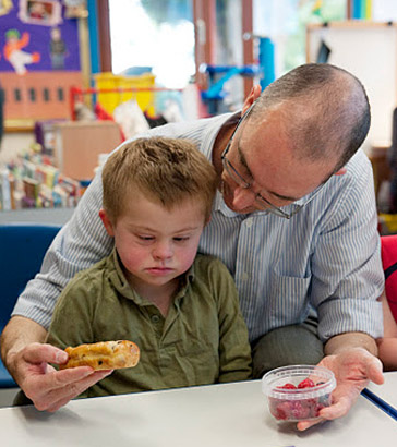 A carer holds two food items in
                  front of a boy