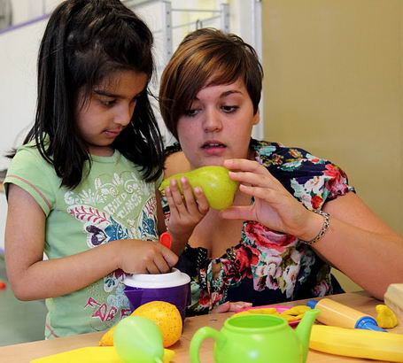 A girl examines a pear with her teacher