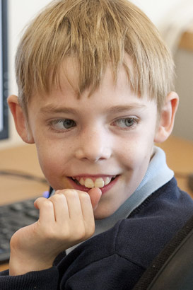 A boy sits in front of a computer
                  screen